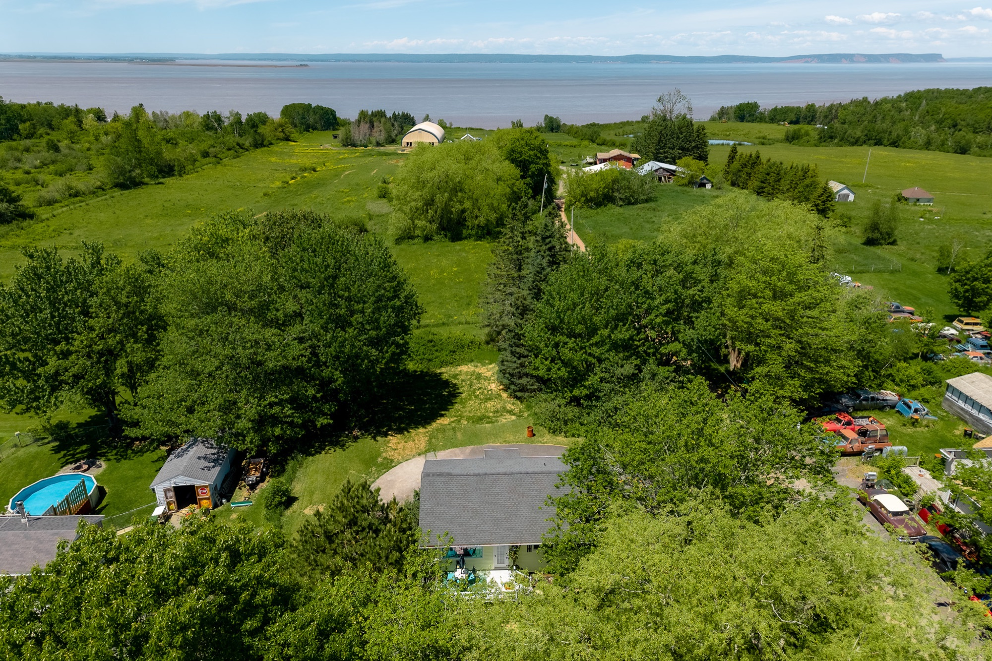 Aerial of the home nestled among trees with the Minas Basin beyond