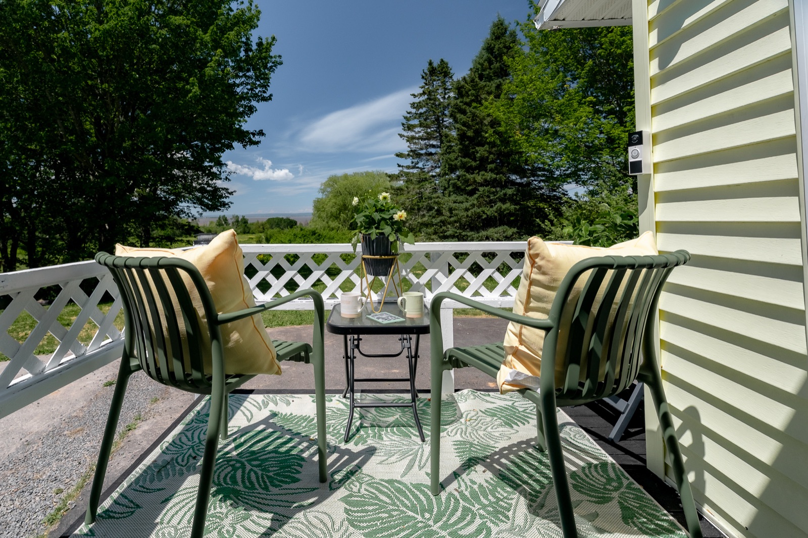 Two green chairs and a bistro table on the back deck