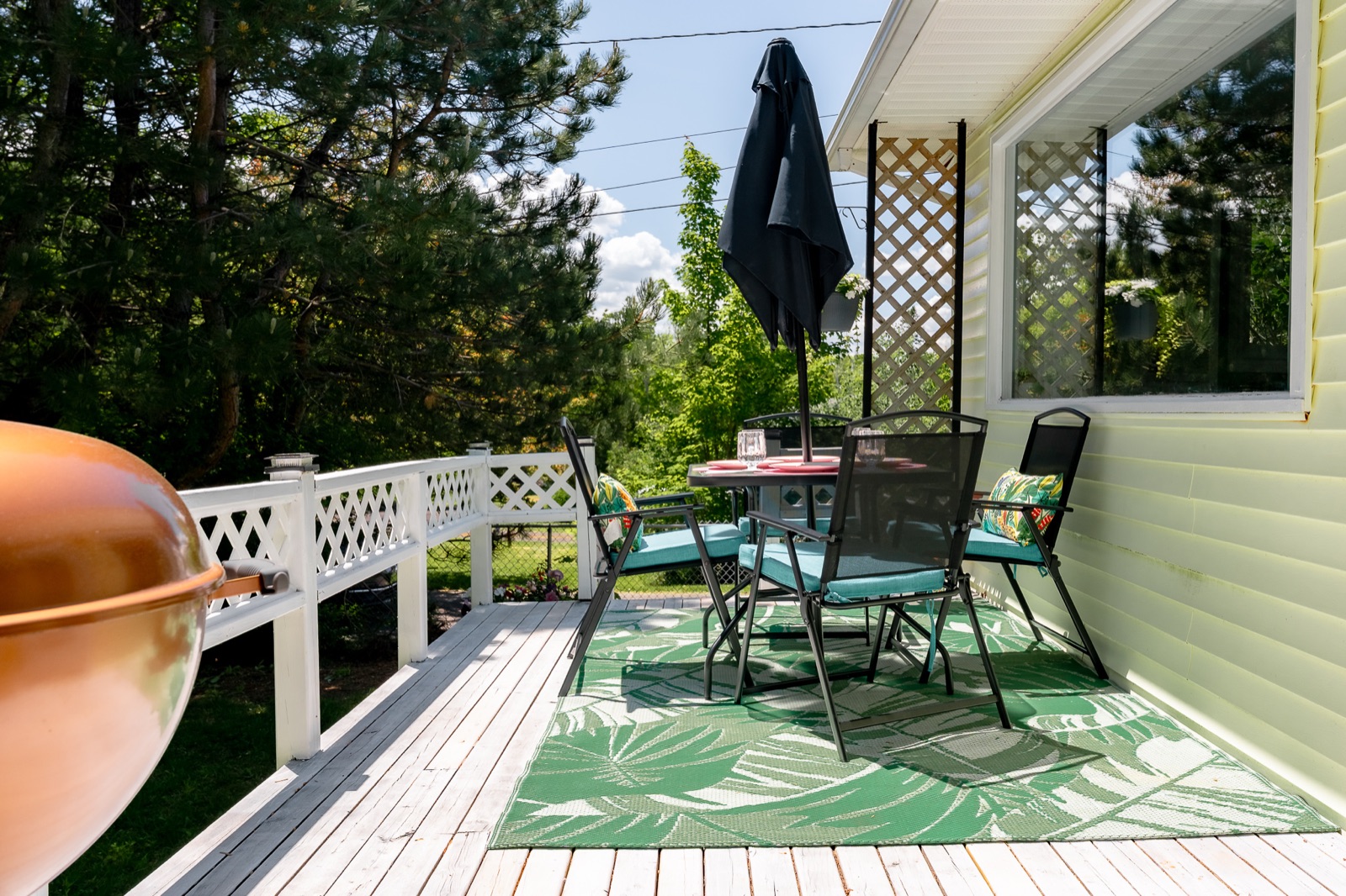 Front deck dining set with umbrella and a treed outlook