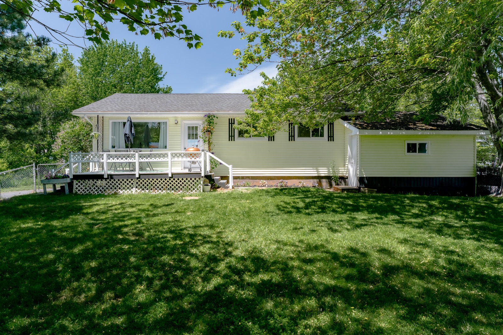 The sage-green bungalow with its white wraparound deck and manicured lawn