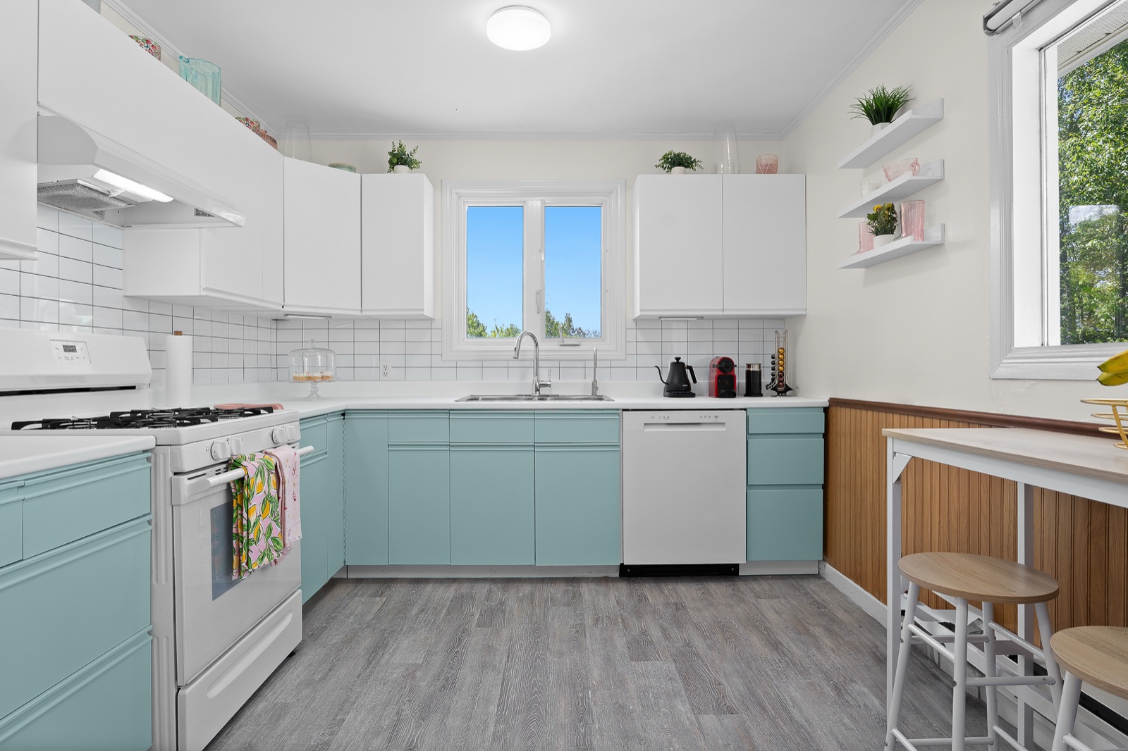 Renovated kitchen with sage cabinets, subway tile, and picture window